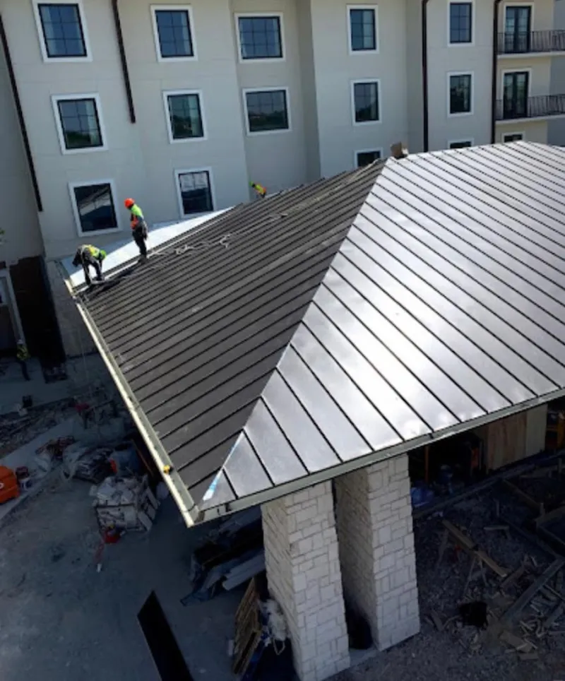Crew installing standing seam metal roof panels on a commercial project in Brewer